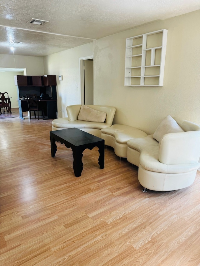 living room with light hardwood / wood-style flooring and a textured ceiling