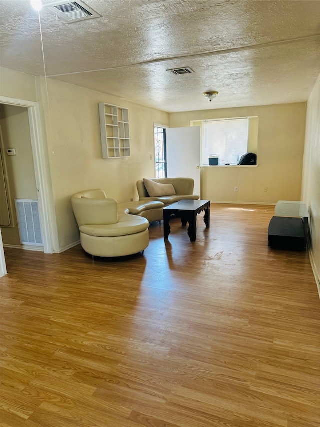 living room featuring light hardwood / wood-style floors and a textured ceiling