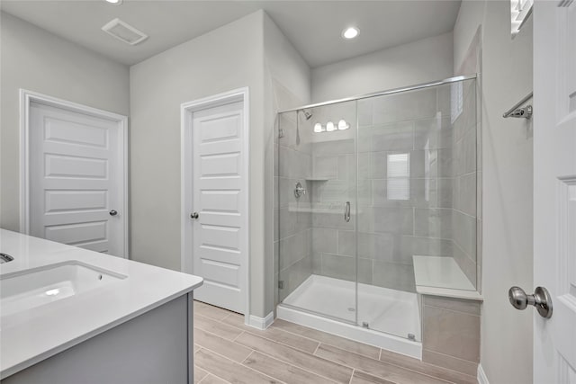 bathroom featuring a shower with door and vanity