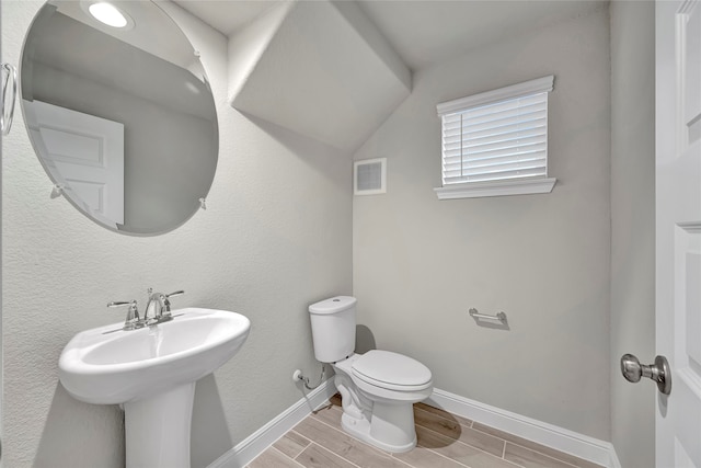 bathroom featuring sink, toilet, vaulted ceiling, and hardwood / wood-style floors