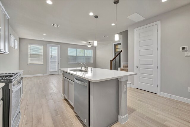 kitchen with a center island with sink, ceiling fan, light hardwood / wood-style flooring, stainless steel appliances, and decorative light fixtures