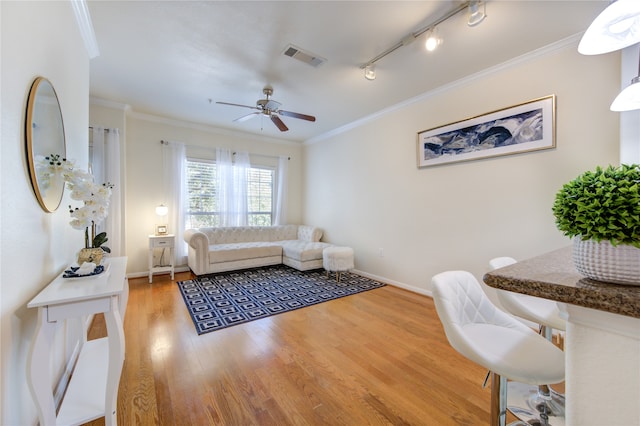 living room featuring rail lighting, ceiling fan, hardwood / wood-style flooring, and ornamental molding