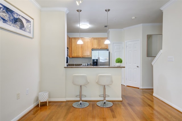 kitchen featuring stainless steel fridge, crown molding, pendant lighting, and light hardwood / wood-style floors