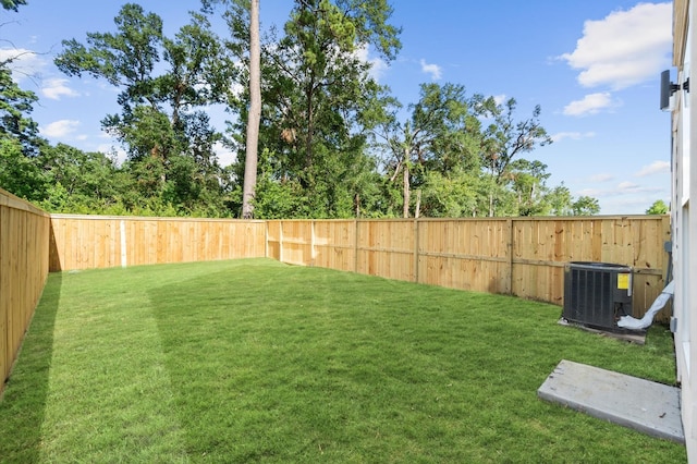 view of yard with a fenced backyard and central AC unit