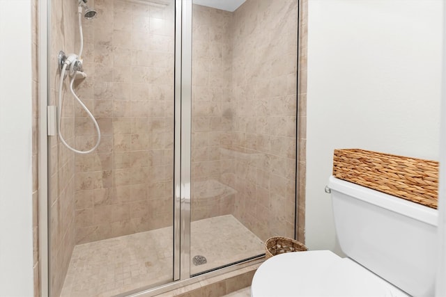 bathroom featuring a shower with shower door and toilet