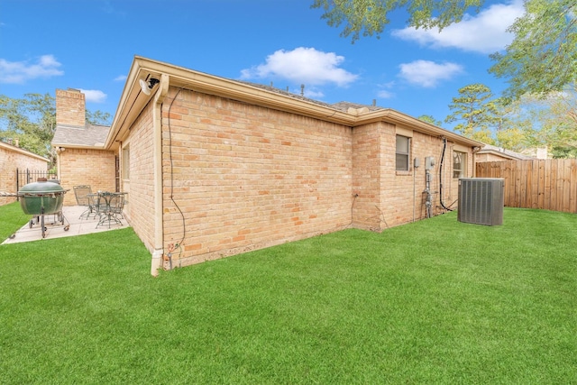 back of house featuring fence, brick siding, a chimney, cooling unit, and a patio