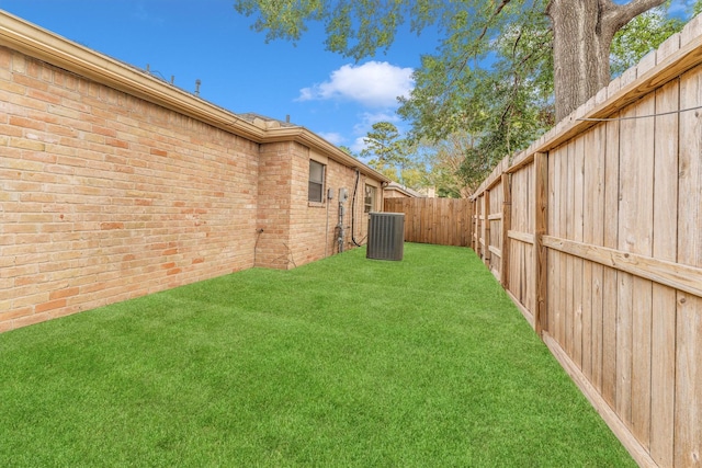 view of yard with a fenced backyard and central AC unit