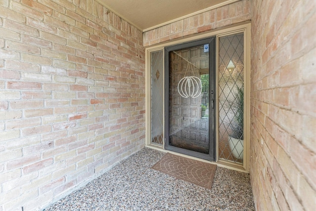 view of exterior entry featuring brick siding