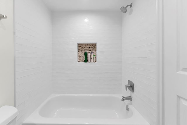 bathroom with toilet and tiled shower / bath