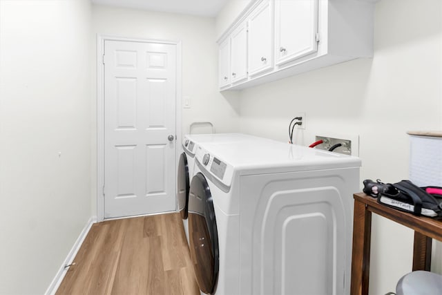 laundry area with cabinets, washer and dryer, and light hardwood / wood-style floors