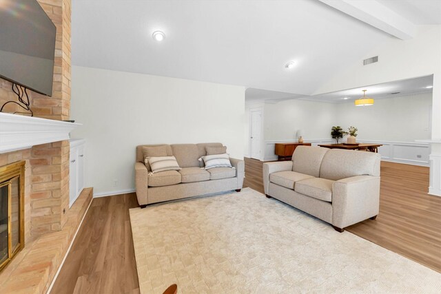 living area with visible vents, a large fireplace, wood finished floors, lofted ceiling with beams, and recessed lighting
