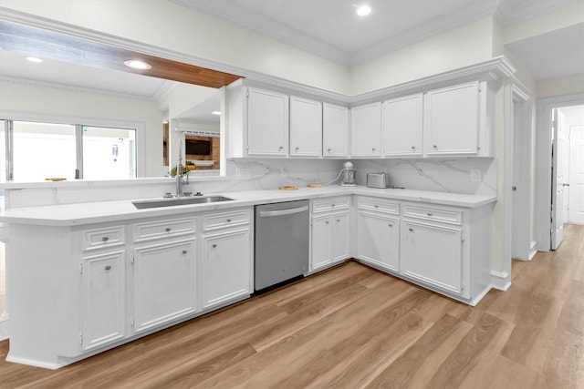 kitchen with ornamental molding, light countertops, white cabinets, a sink, and dishwasher