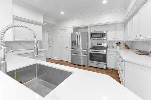 kitchen featuring ornamental molding, wood finished floors, recessed lighting, white cabinets, and stainless steel appliances