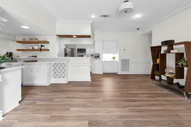 kitchen with appliances with stainless steel finishes, light hardwood / wood-style flooring, white cabinets, and ornamental molding