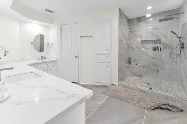 bathroom featuring vanity, a tile shower, and tile patterned floors