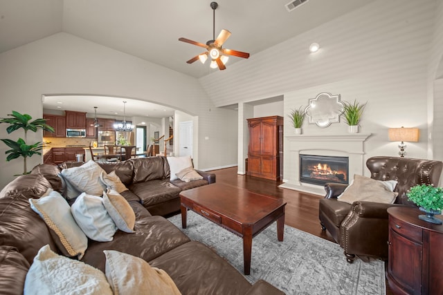 living room featuring lofted ceiling, hardwood / wood-style flooring, and ceiling fan with notable chandelier