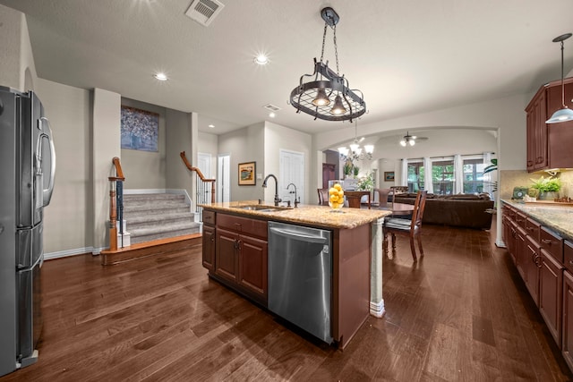 kitchen with stainless steel appliances, sink, an island with sink, and decorative light fixtures