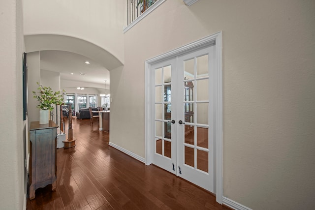 hallway with french doors, a notable chandelier, and dark hardwood / wood-style flooring