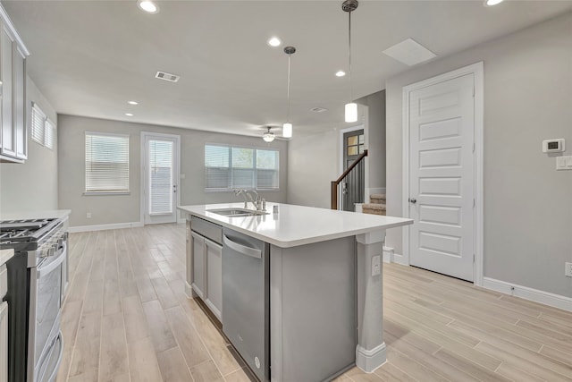 kitchen featuring ceiling fan, an island with sink, light wood-type flooring, pendant lighting, and stainless steel appliances