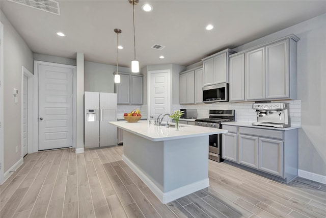 kitchen featuring pendant lighting, sink, gray cabinets, appliances with stainless steel finishes, and decorative backsplash