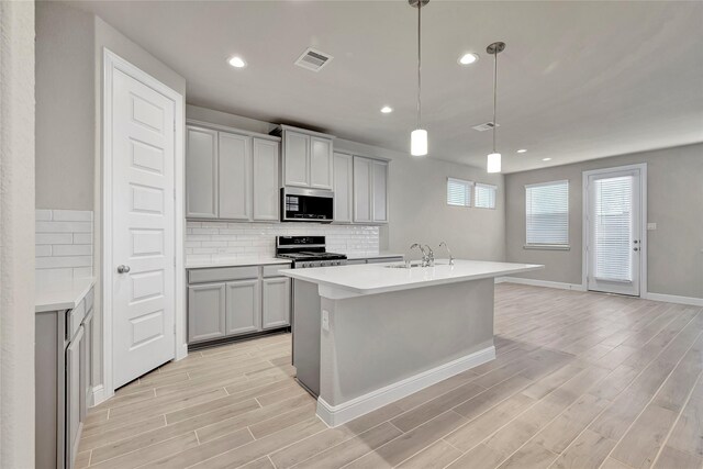 kitchen featuring gray cabinetry, stainless steel appliances, sink, decorative light fixtures, and light hardwood / wood-style floors