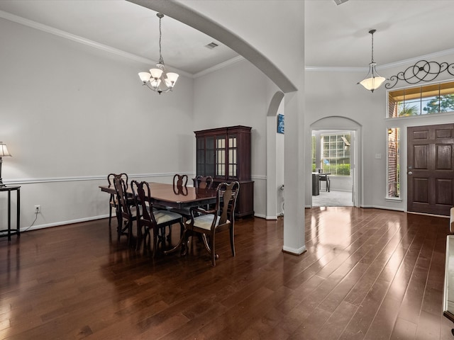 dining space featuring dark hardwood / wood-style flooring, crown molding, a high ceiling, and an inviting chandelier