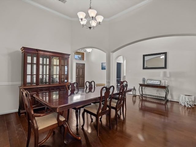 dining room with a notable chandelier, dark hardwood / wood-style flooring, ornamental molding, and a high ceiling