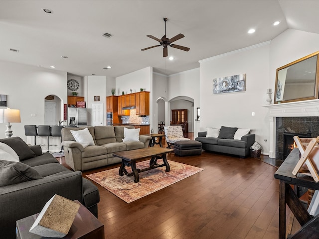 living room featuring a high end fireplace, ornamental molding, ceiling fan, and dark wood-type flooring