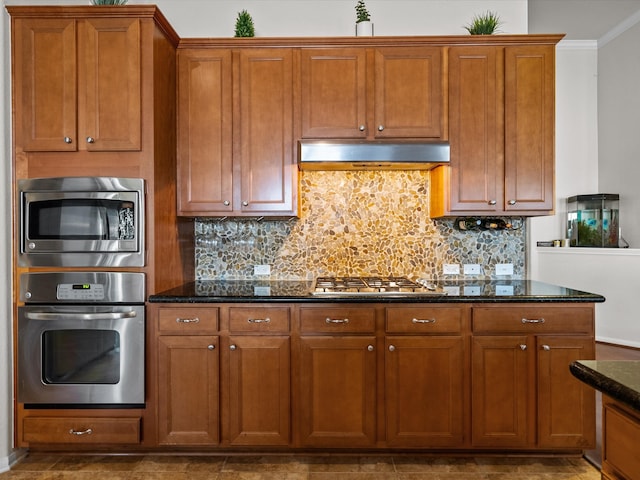 kitchen with dark stone countertops, decorative backsplash, stainless steel appliances, and ornamental molding