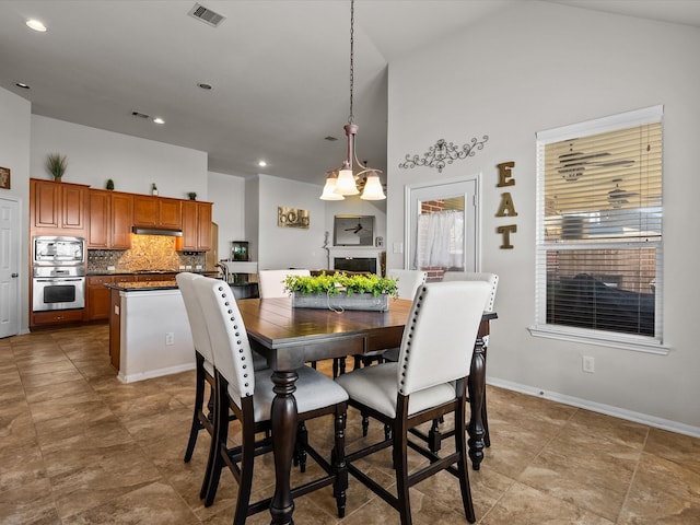 dining space with high vaulted ceiling and an inviting chandelier