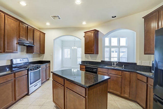 kitchen featuring appliances with stainless steel finishes, sink, a kitchen island, dark stone countertops, and an inviting chandelier