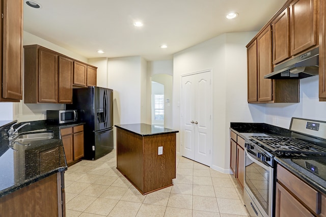 kitchen with stainless steel appliances, sink, dark stone counters, and a kitchen island