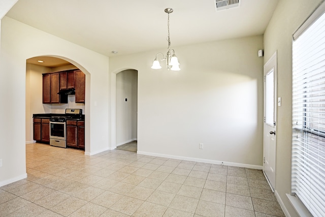 kitchen featuring exhaust hood, an inviting chandelier, stainless steel stove, and hanging light fixtures