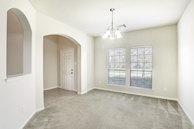 carpeted empty room with a notable chandelier