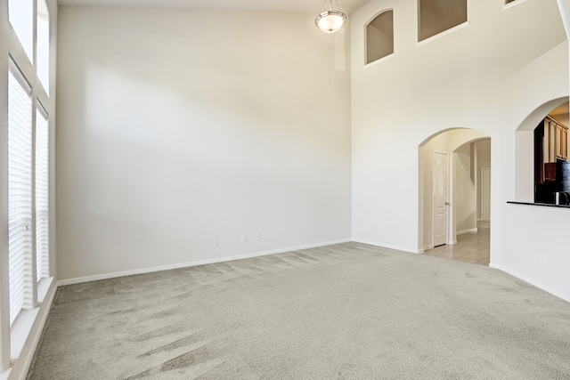 carpeted empty room with high vaulted ceiling