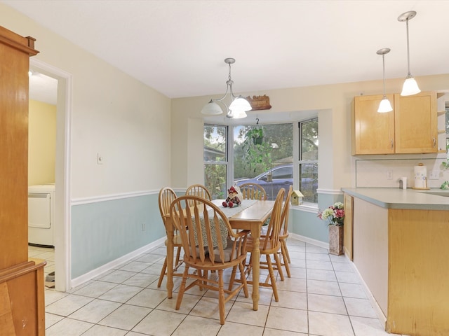 dining room with washer / dryer, a notable chandelier, and light tile patterned floors