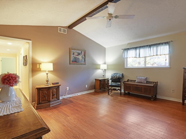 sitting room featuring ceiling fan, vaulted ceiling with beams, and hardwood / wood-style floors