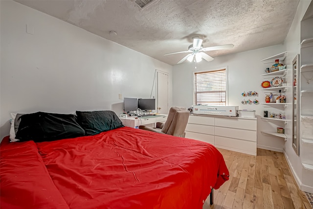 bedroom featuring a textured ceiling, light wood-type flooring, and ceiling fan