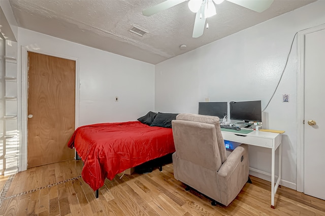 bedroom with a textured ceiling, light hardwood / wood-style floors, and ceiling fan