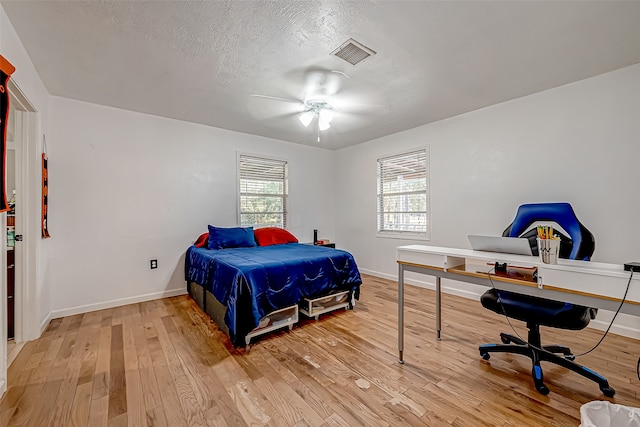 bedroom featuring ceiling fan, wood-type flooring, and a textured ceiling