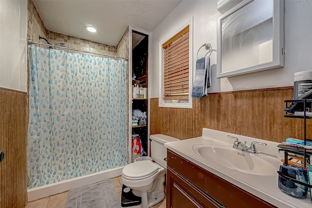 bathroom featuring walk in shower, vanity, tile patterned flooring, toilet, and wood walls