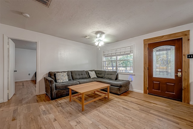 living room with ceiling fan, light hardwood / wood-style floors, and a textured ceiling