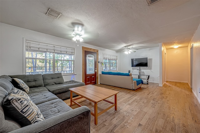 living room with ceiling fan, light hardwood / wood-style floors, and a textured ceiling