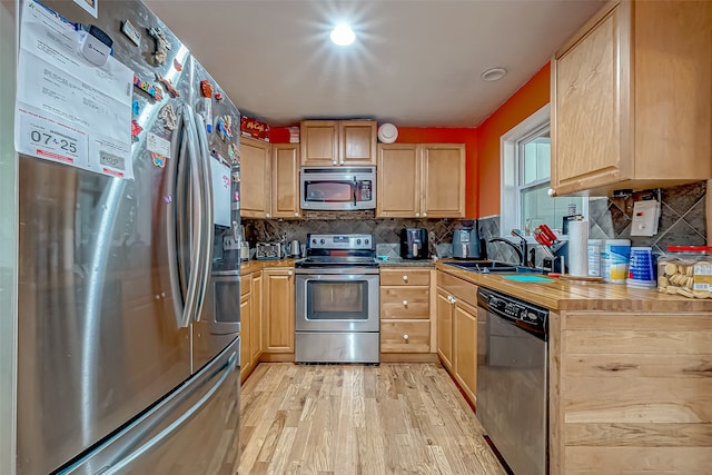 kitchen with decorative backsplash, appliances with stainless steel finishes, light brown cabinetry, sink, and light hardwood / wood-style flooring