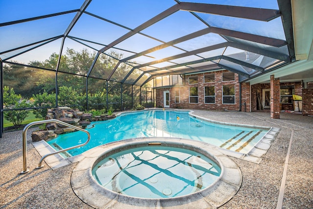 view of pool with glass enclosure, an in ground hot tub, and a patio area