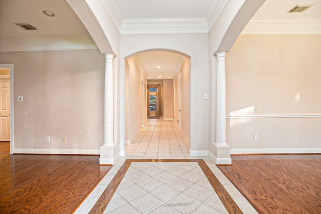 corridor with crown molding, decorative columns, and light tile patterned floors