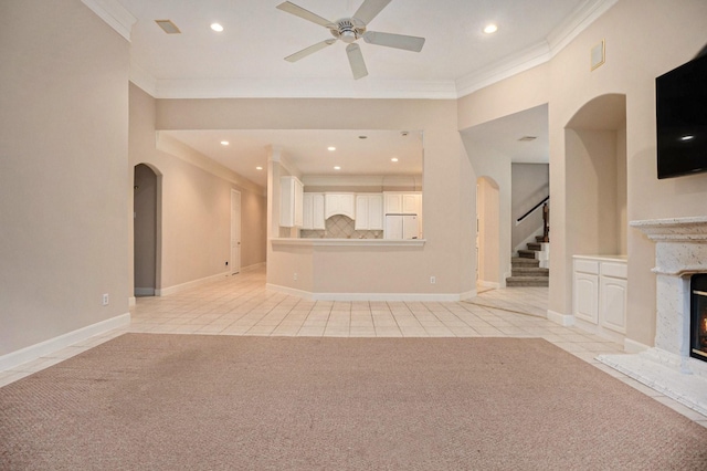 unfurnished living room with ornamental molding, a premium fireplace, ceiling fan, and light tile patterned floors