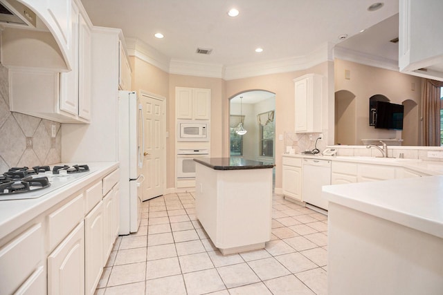 kitchen with white appliances, ventilation hood, and white cabinetry