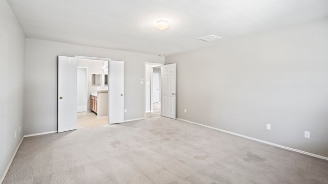 unfurnished bedroom with light colored carpet and ensuite bath