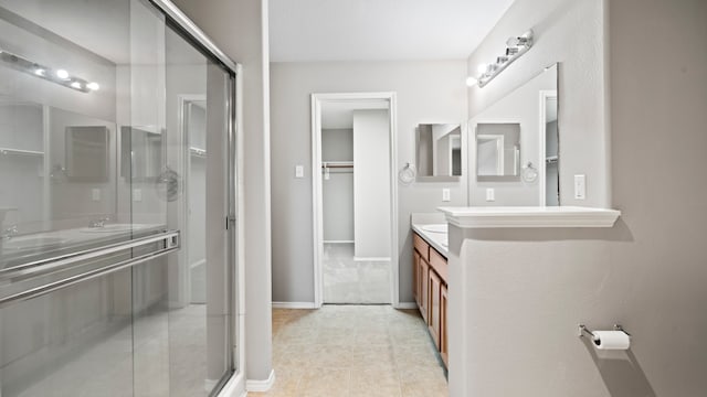 bathroom with a shower with door, vanity, and tile patterned flooring